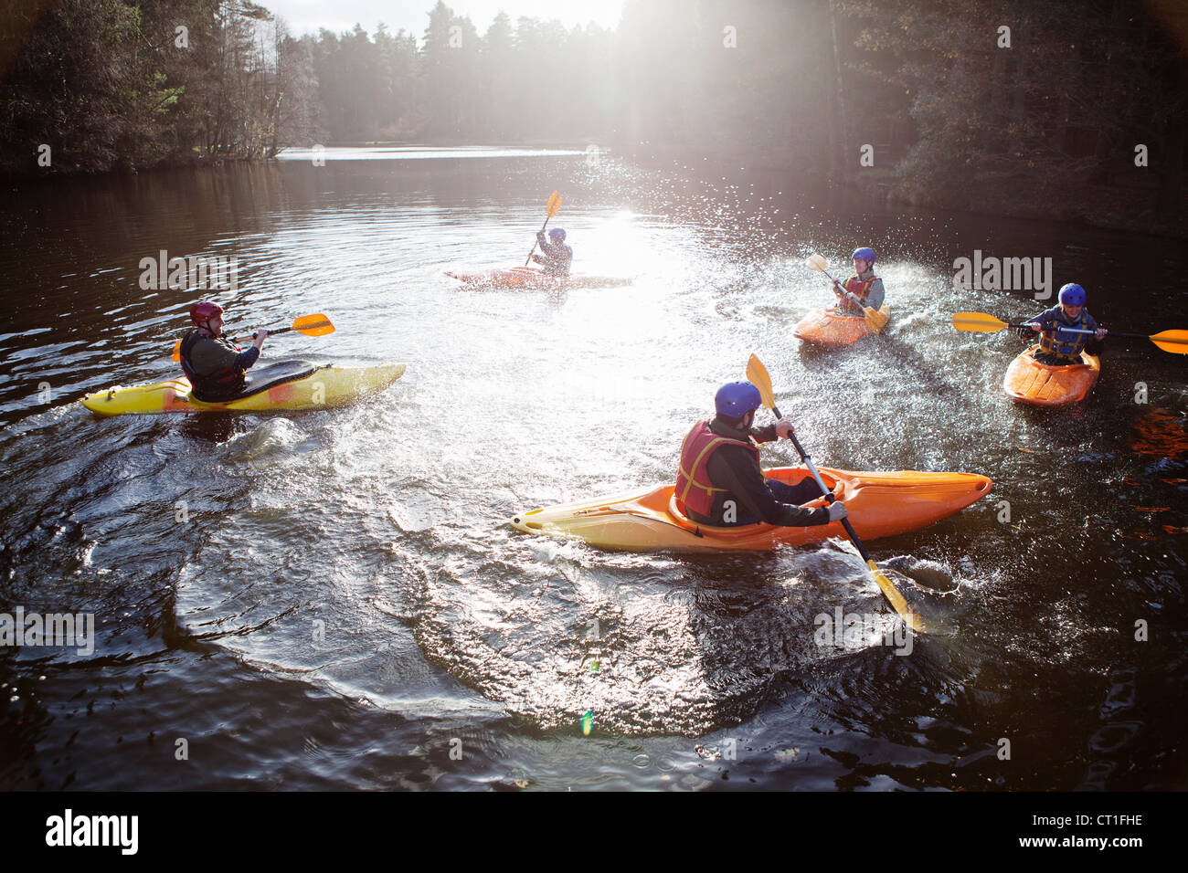 Kayakers rowing in still lake Stock Photo