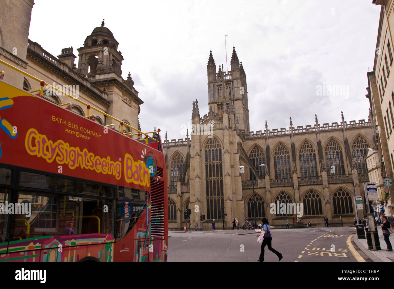 Citysightseeing Bath Bus Company tour bus passes by Bath Abbey Stock