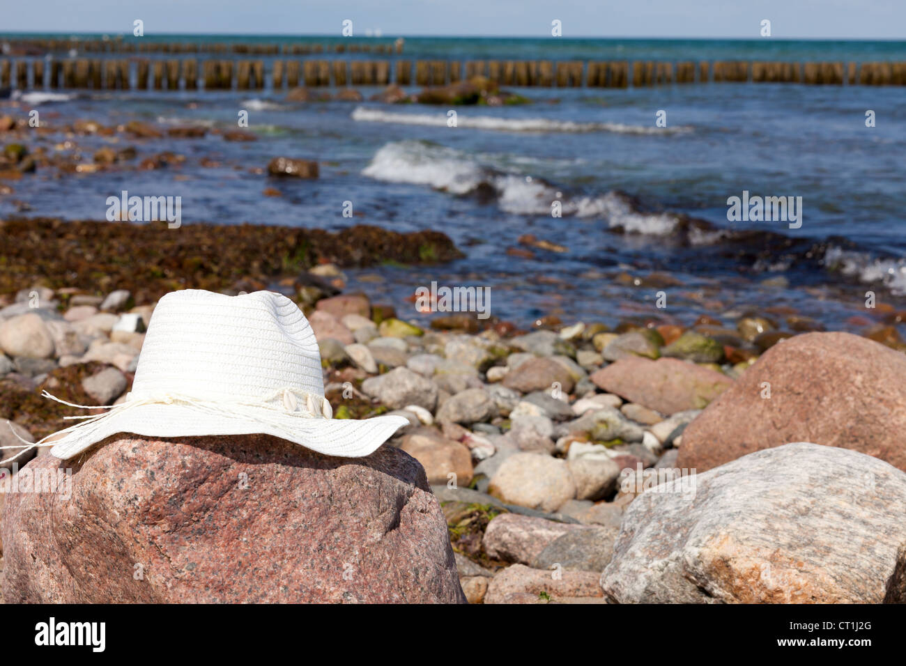 An white straw hat lies on a red big rock on the beach Stock Photo - Alamy