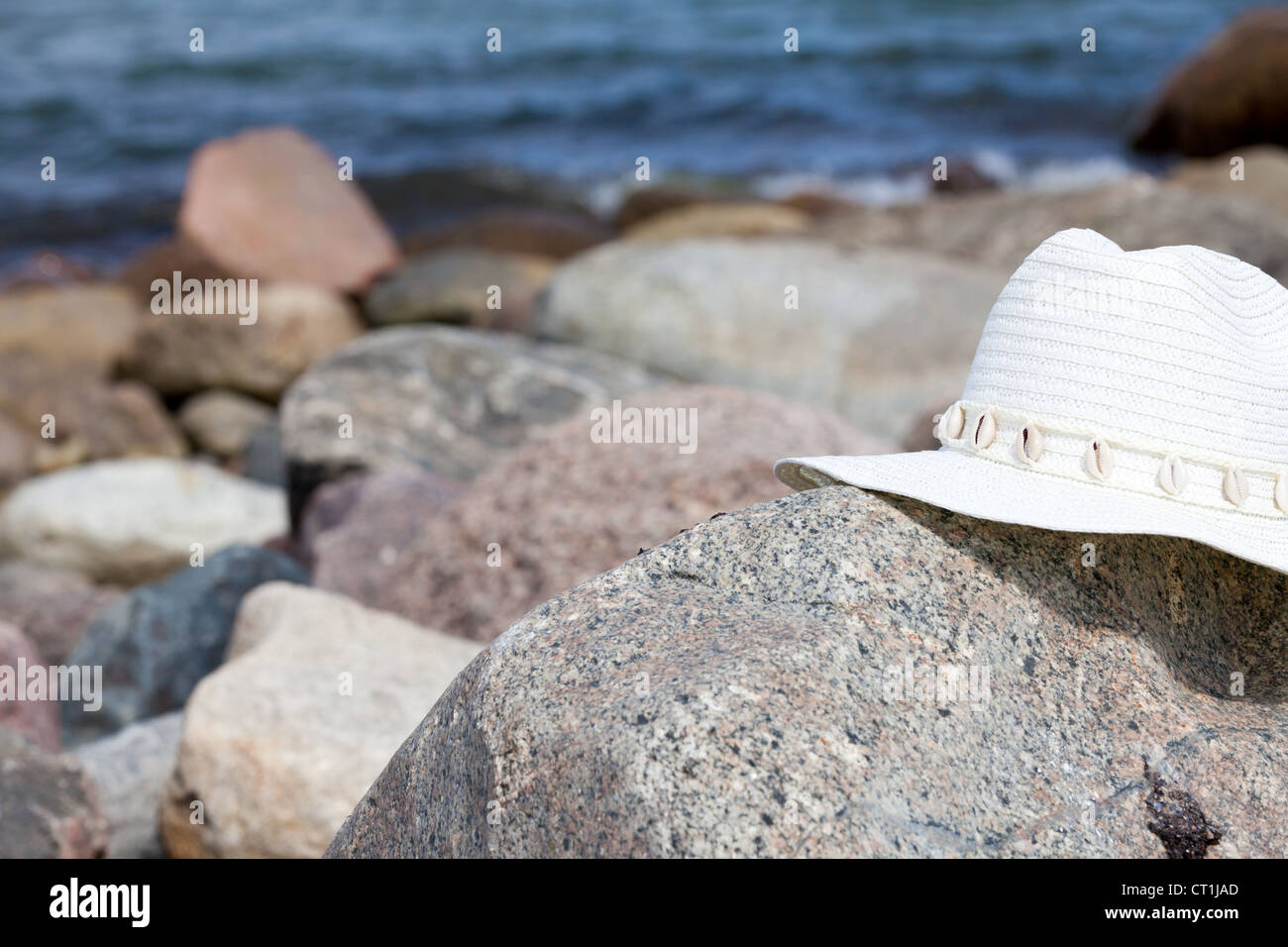 An white straw hat lies on a rock on the beach Stock Photo - Alamy