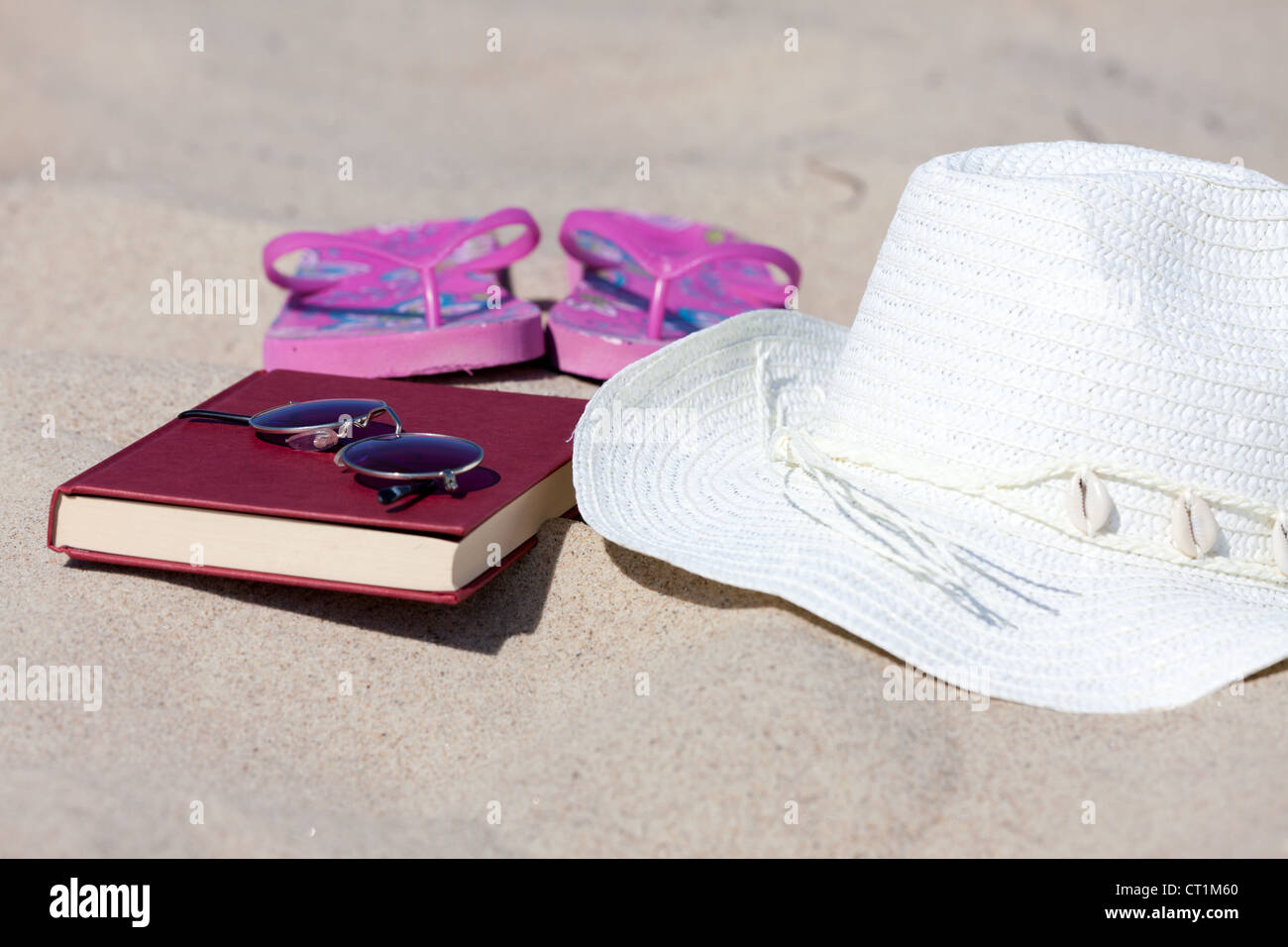 With the straw hat and a book on the beach Stock Photo - Alamy