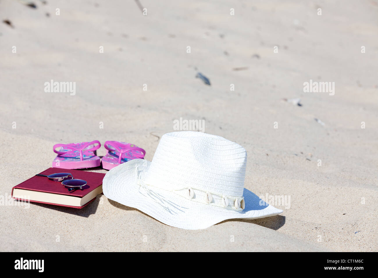 With the straw hat and a book on the beach Stock Photo - Alamy