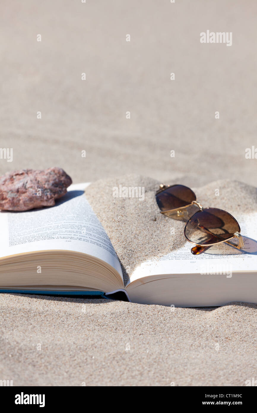 Sunglasses lies on an opened book on the beach Stock Photo - Alamy
