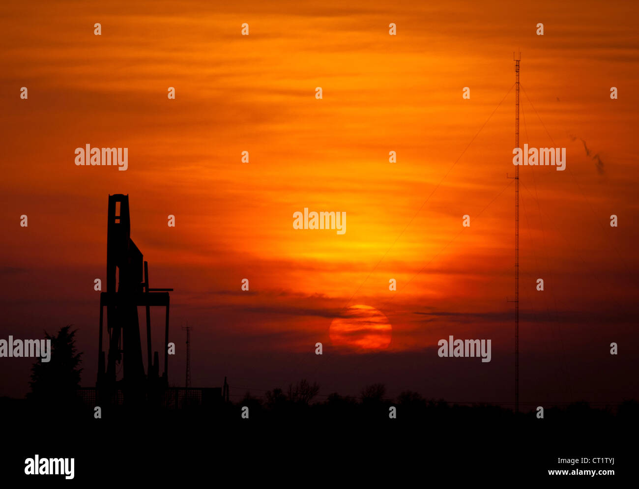 The Sun setting behind an oil pump Stock Photo