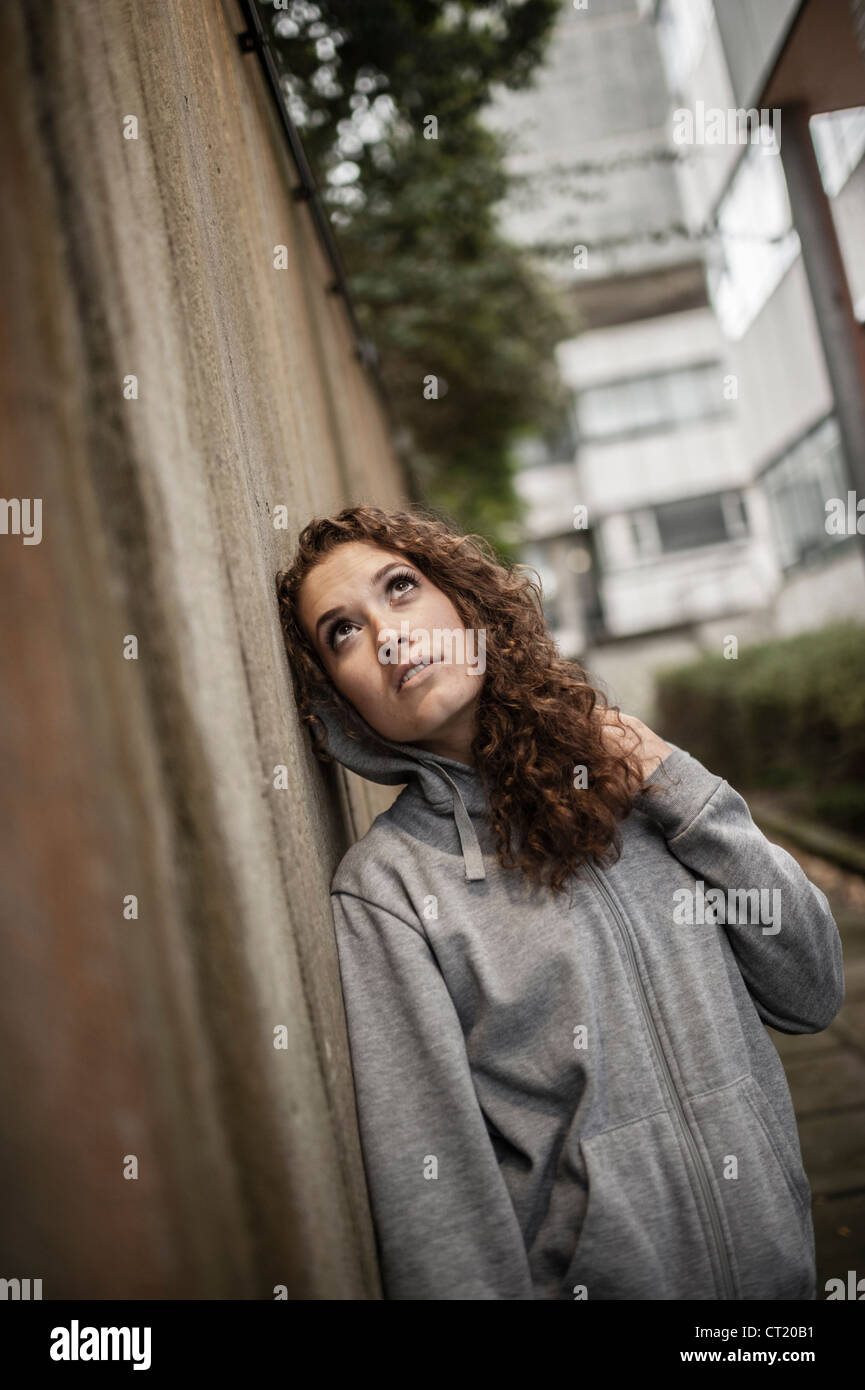 A young 20 year old slim attractive woman girl alone urban city wearing a grey hoody UK Stock Photo
