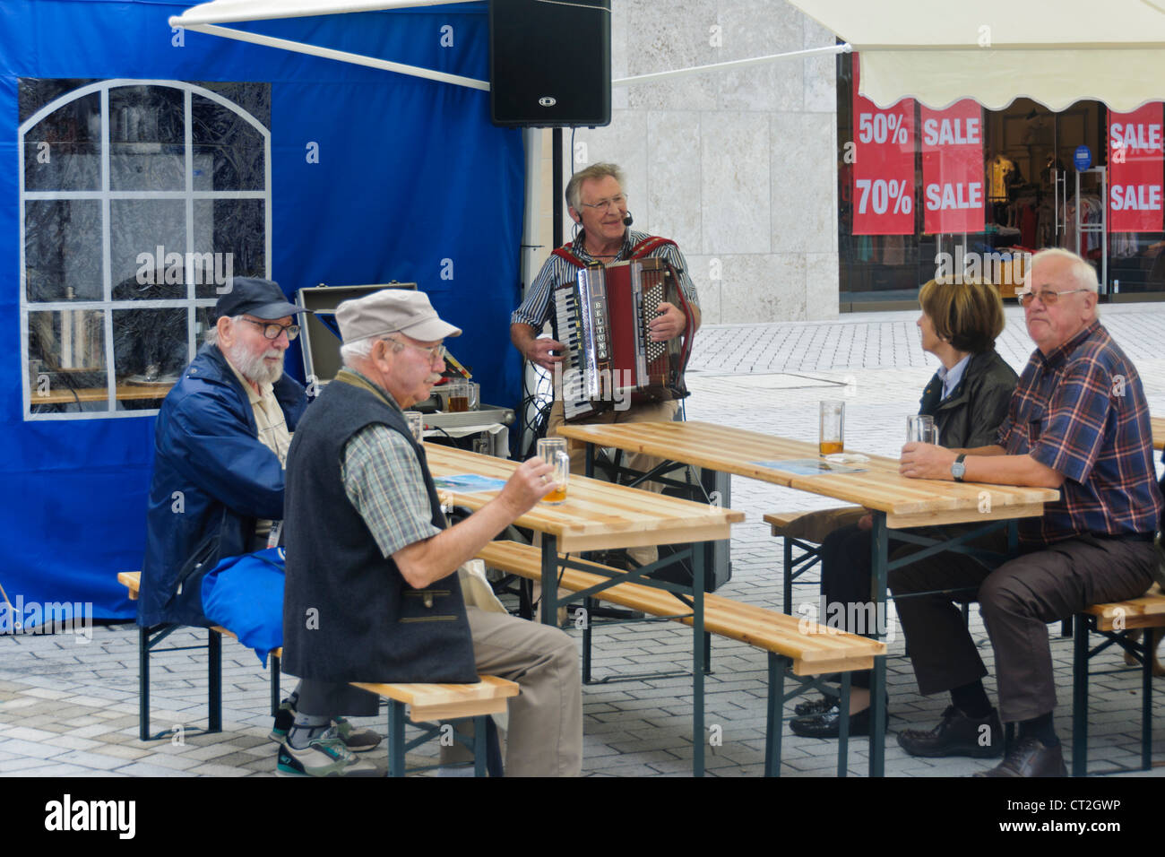 German Pensioners Senior Citizens sit at ale-benches listening accordion player - Heilbronn, Germany Stock Photo