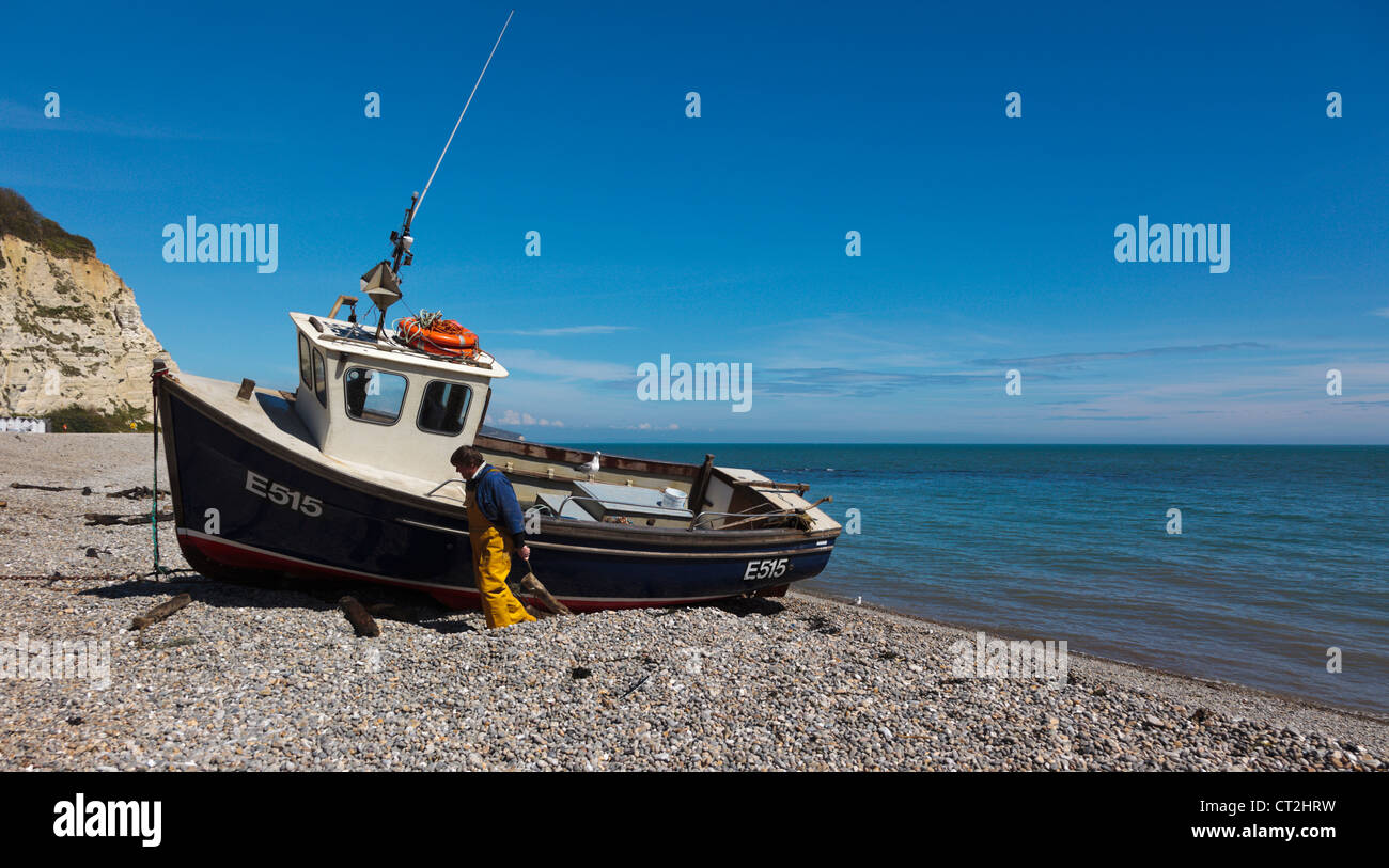 Fishing boat being winched up onto the pebble beach at Beer Devon England UK Stock Photo