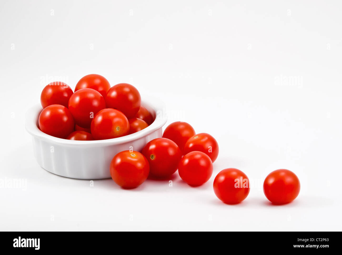 Red cherry tomatoes in white bowl on white background Stock Photo - Alamy