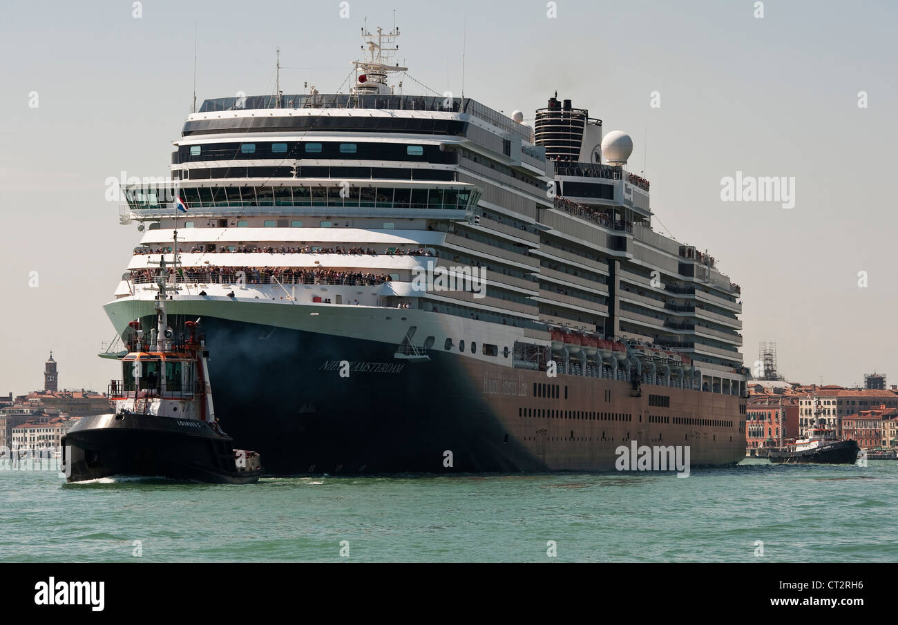 Tugs towing the huge cruise ship Nieuw Amsterdam into Venice, Italy. It belongs to the Holland America Line Stock Photo