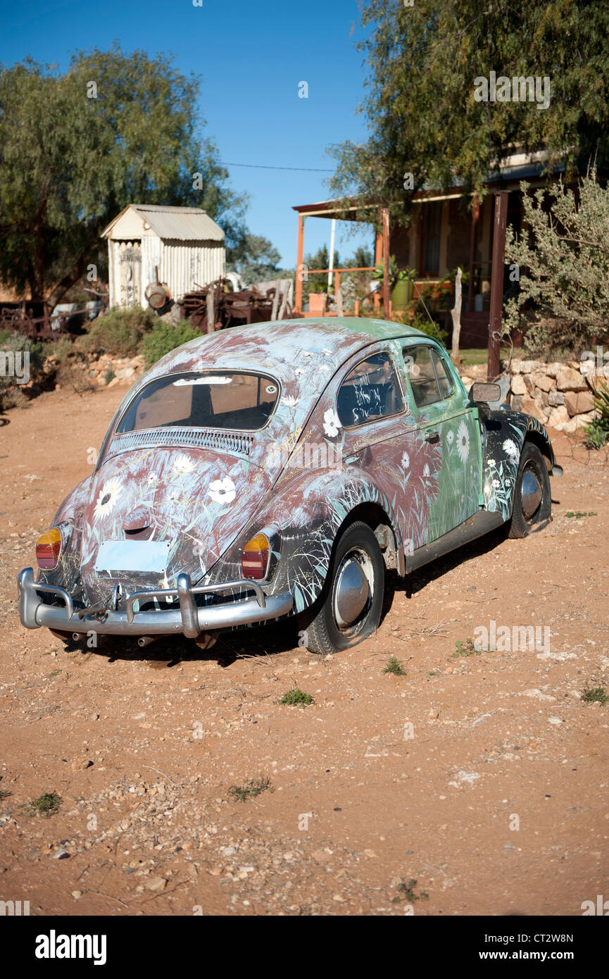 Colourful painted VW beetle car in front of a historic homestead of ...