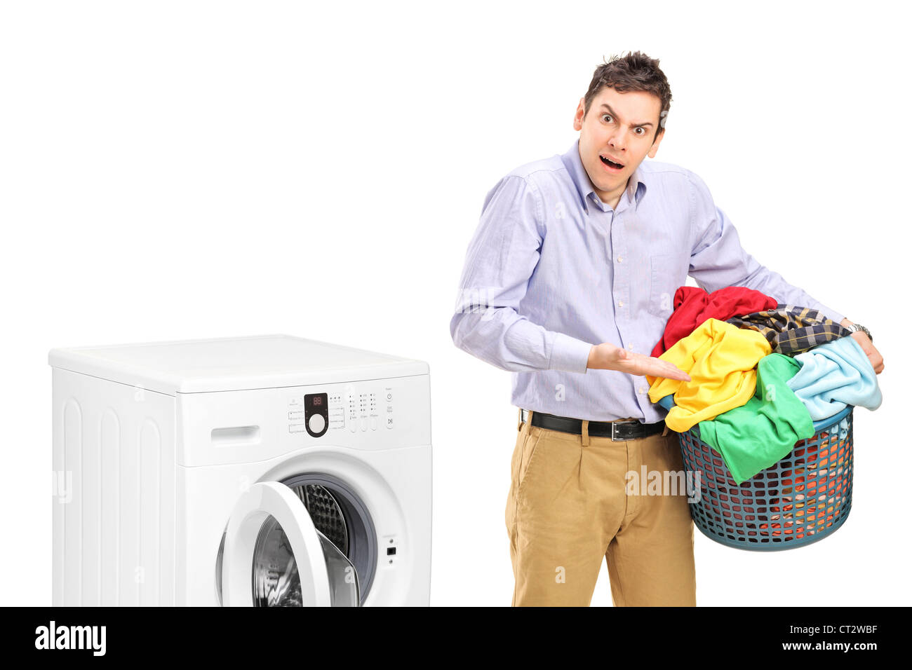 Young man holding a laundry basket and gesturing near a washing machine isolated on white background Stock Photo
