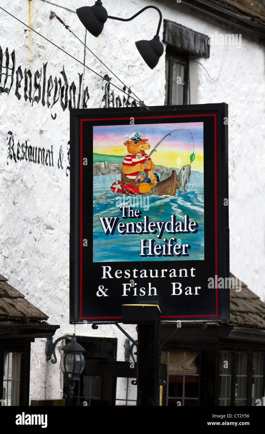 The Wensleydale Heifer restaurant sign & cartoon illustration fish bar sign, West Witton, Yorkshire Dales National Park, UK Stock Photo