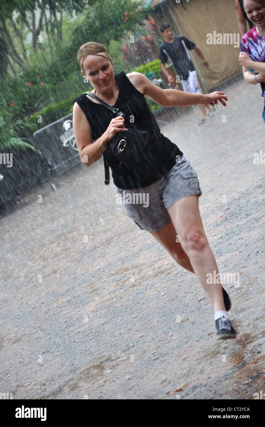 People, including this young lady, dash for cover as the rain pours down during a thunderstorm. Stock Photo