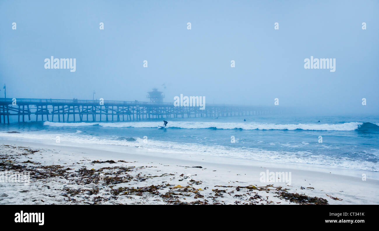 San Clemente pier with surfers on a foggy day Stock Photo