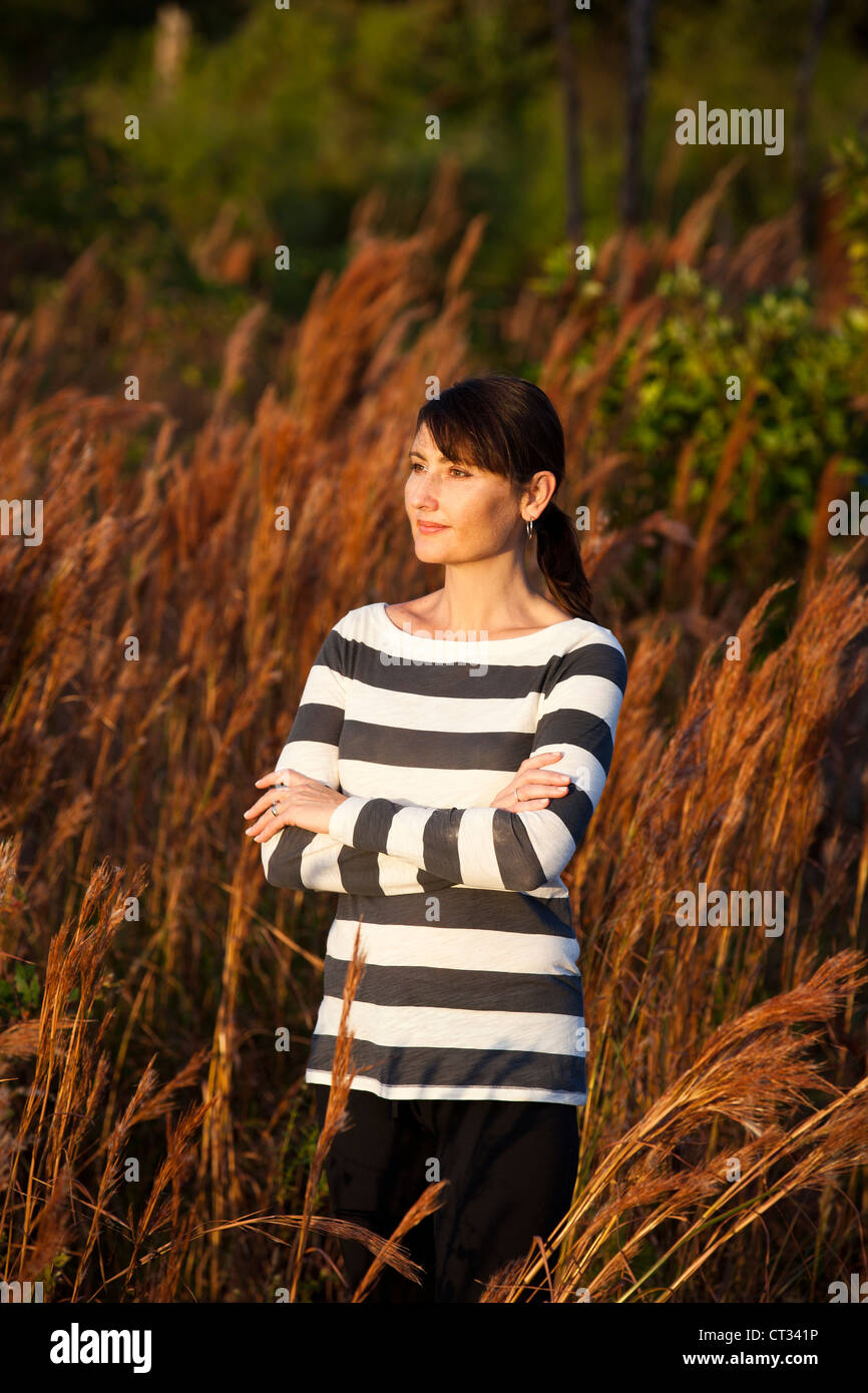 woman folding arms in field Stock Photo