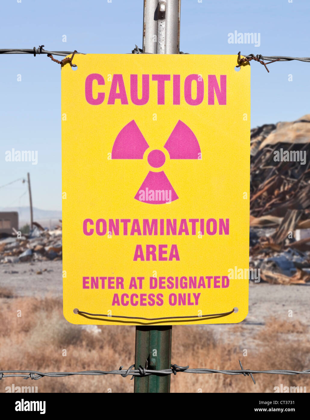 Caution radioactive contamination warning sign with barb wire fence. Stock Photo