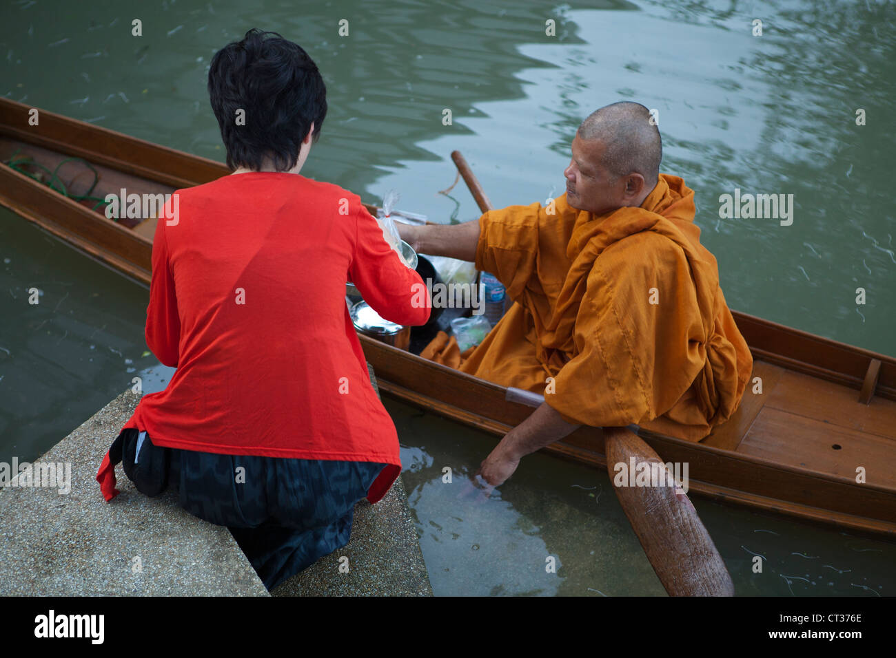 Thai monk travel from temple to temple, and collect alms on their morning rounds by boat in Amphawa. Stock Photo