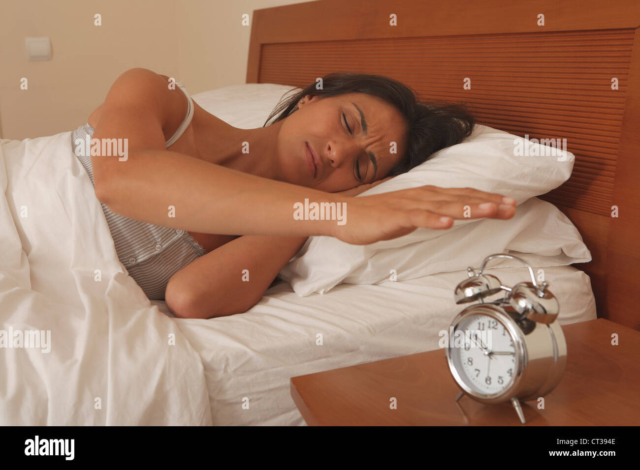 Woman turning off alarm clock Stock Photo