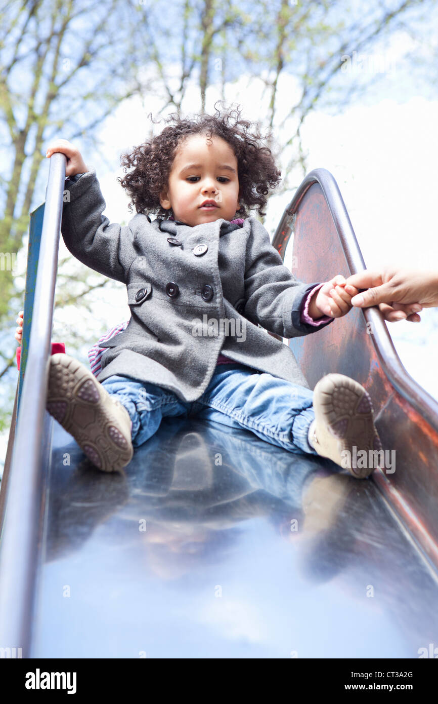 Girl playing on slide in playground Stock Photo - Alamy