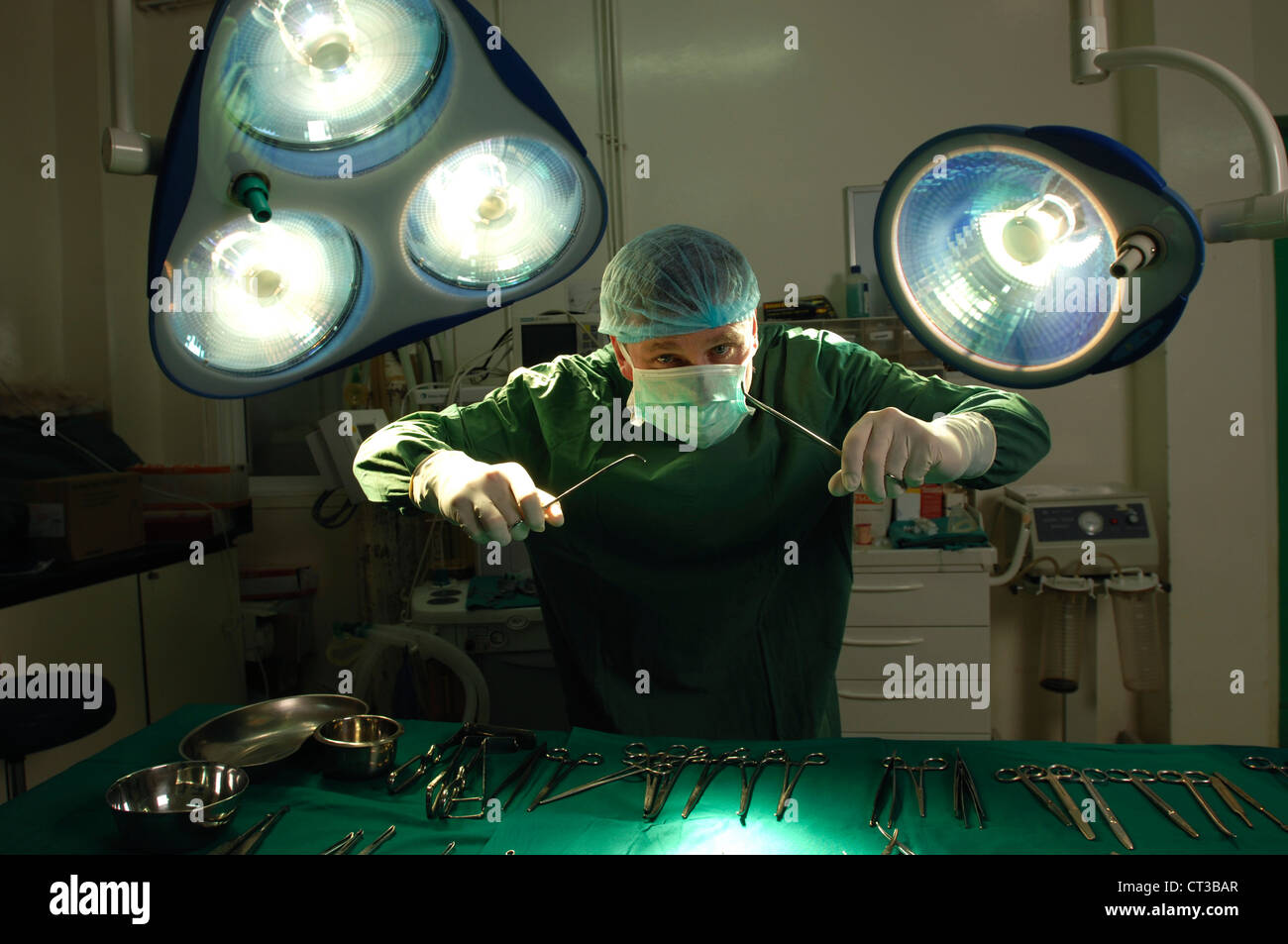 A surgeon brandishing surgical tools in an operating theatre. Stock Photo