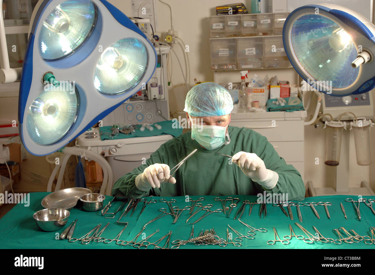 A surgeon in complete surgical dress brandishing surgical tools in an operating theatre. Stock Photo