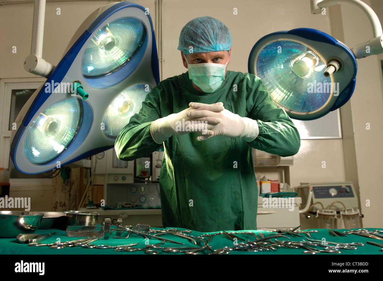 A surgeon clasping his hands over a table laden with instruments. Stock Photo