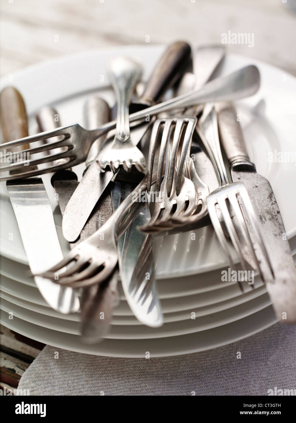 Cutlery piled on stack of plates Stock Photo Alamy