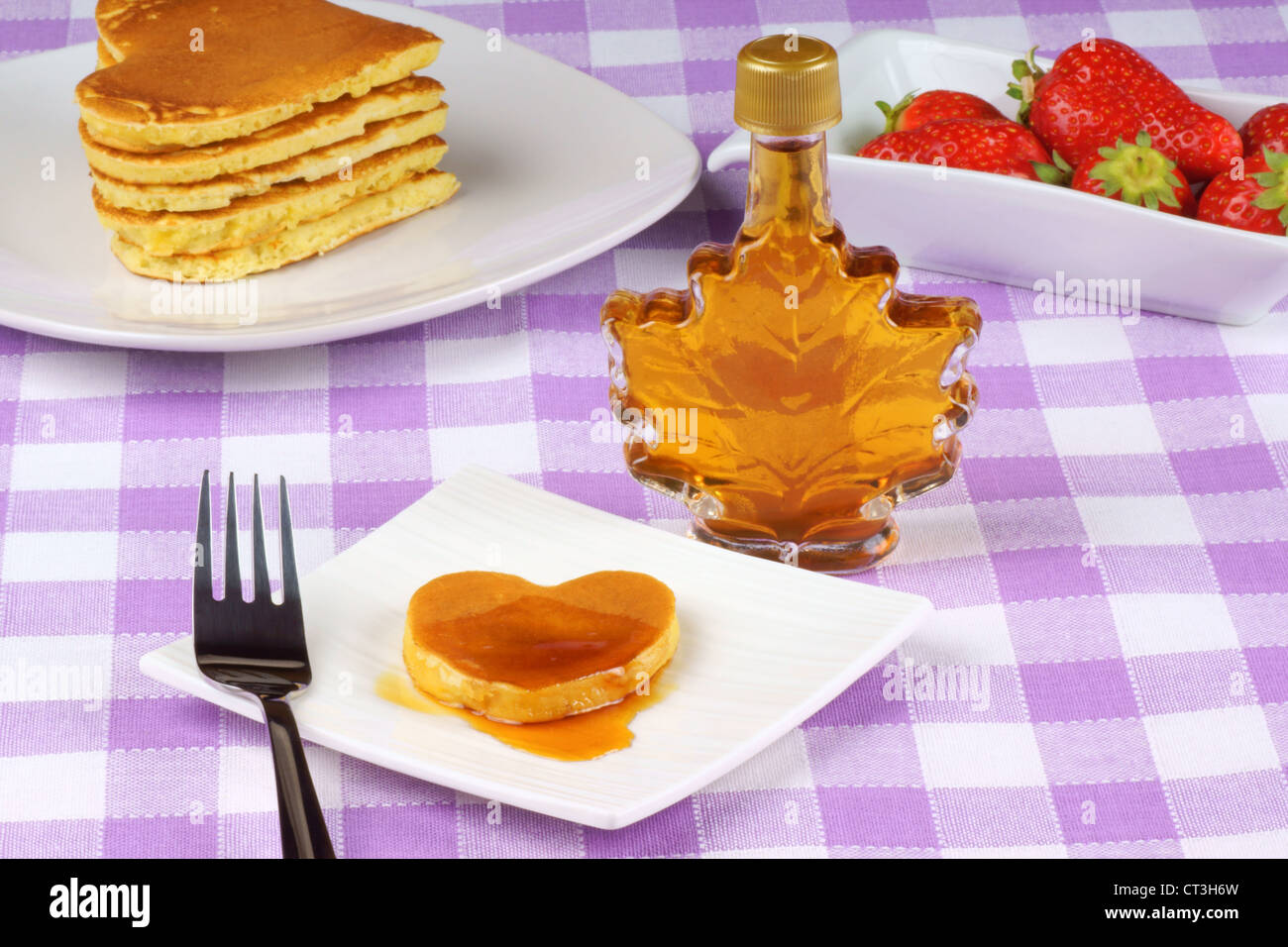 Mini heart-shaped pancake with syrup on a white dish with fork. For Valentine's day breakfast Stock Photo