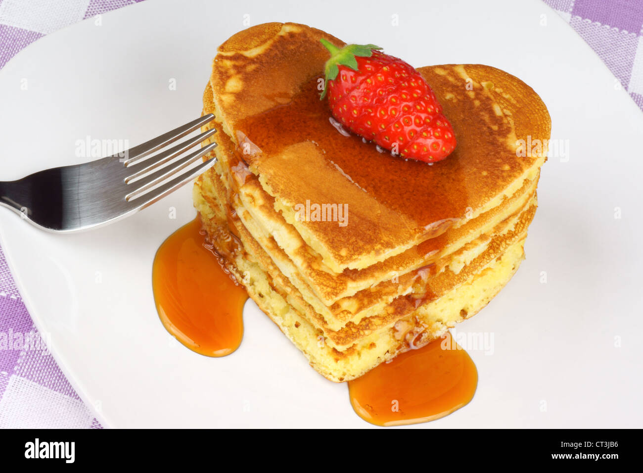 Heart-shaped pancakes with syrup and a strawberry on a white dish. A perfect breakfast for Valentine's Day Stock Photo