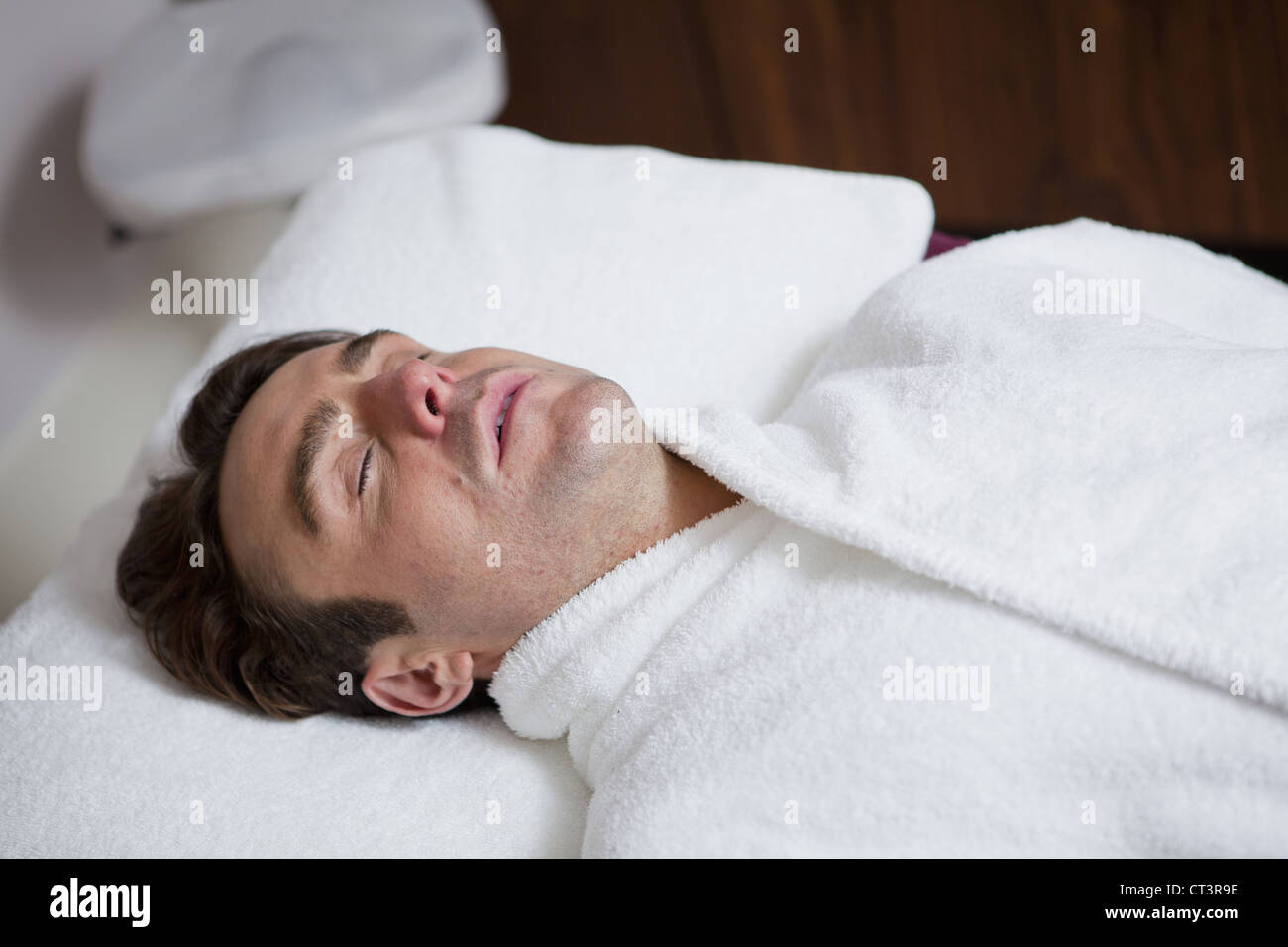 Man in bathrobe sleeping on cot Stock Photo Alamy