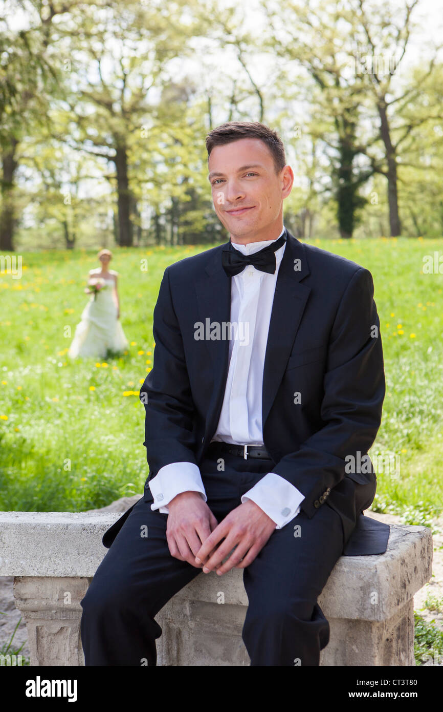 Smiling groom sitting on wall Stock Photo