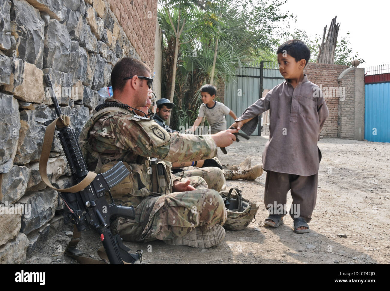 A US Airborne paratroopers greet children during a security patrol outside of Forward Operating Base Salerno July 7, 2012 in Kunday, Afghanistan. Soldiers provided security for a midwife program held at a girls school in the village. Stock Photo