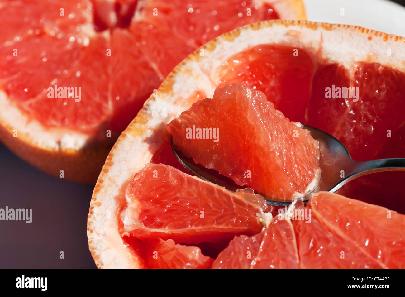 Closeup view of grapefruit halves with a spoon  holding a section ready for eating. Stock Photo