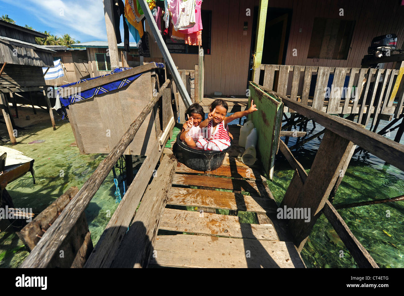Malaysia, Borneo, Semporna, Mabul, Dayak Lau (sea gypsies) girls washing inside water bucket Stock Photo