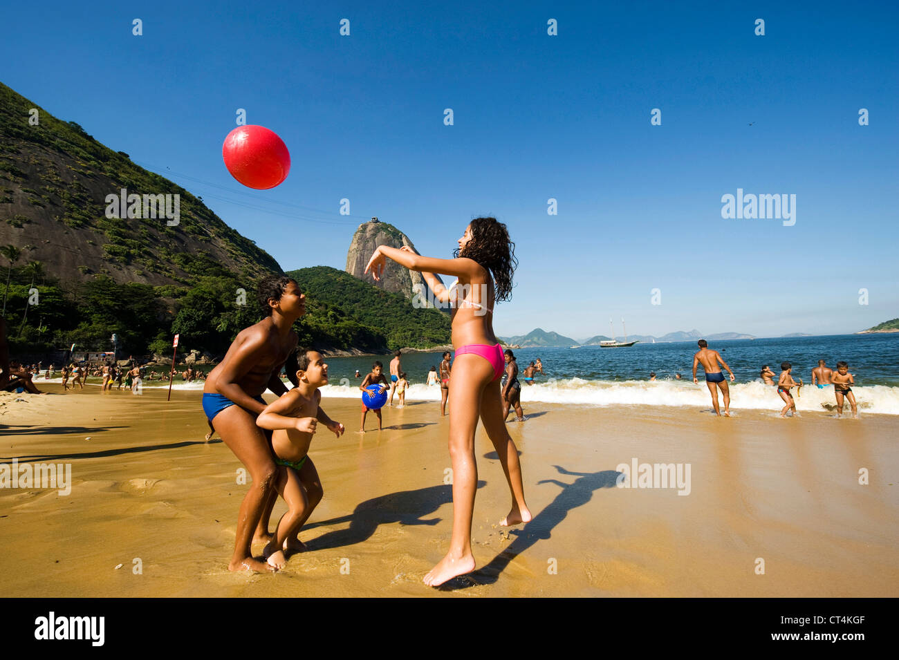 Brazil, Rio de Janeiro, Urca, families playing at the beach with Sugar Loaf in background Stock Photo