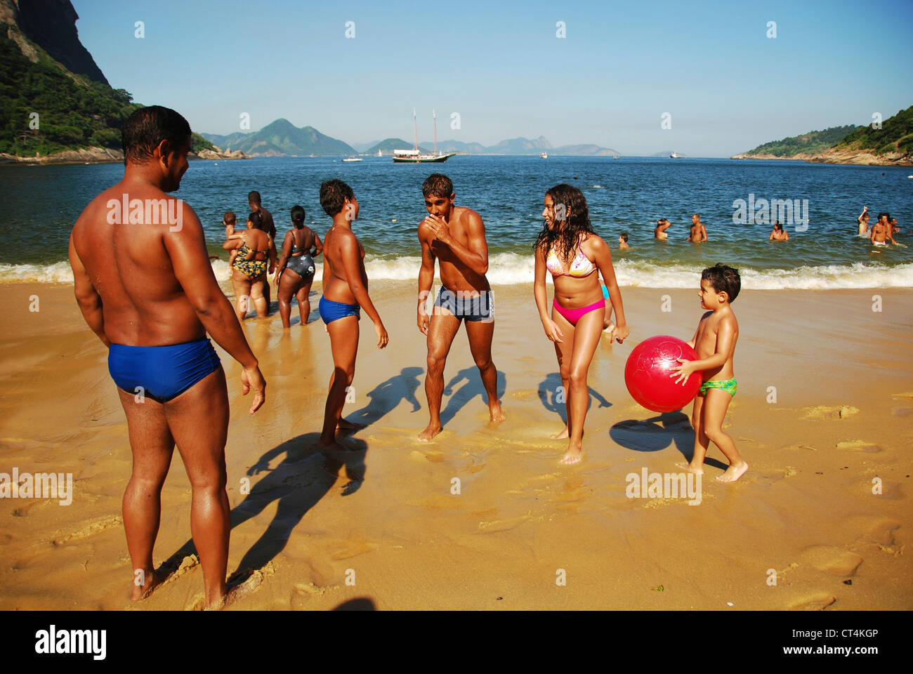Brazil, Rio de Janeiro, Urca, families playing at the beach with Sugar Loaf in background Stock Photo