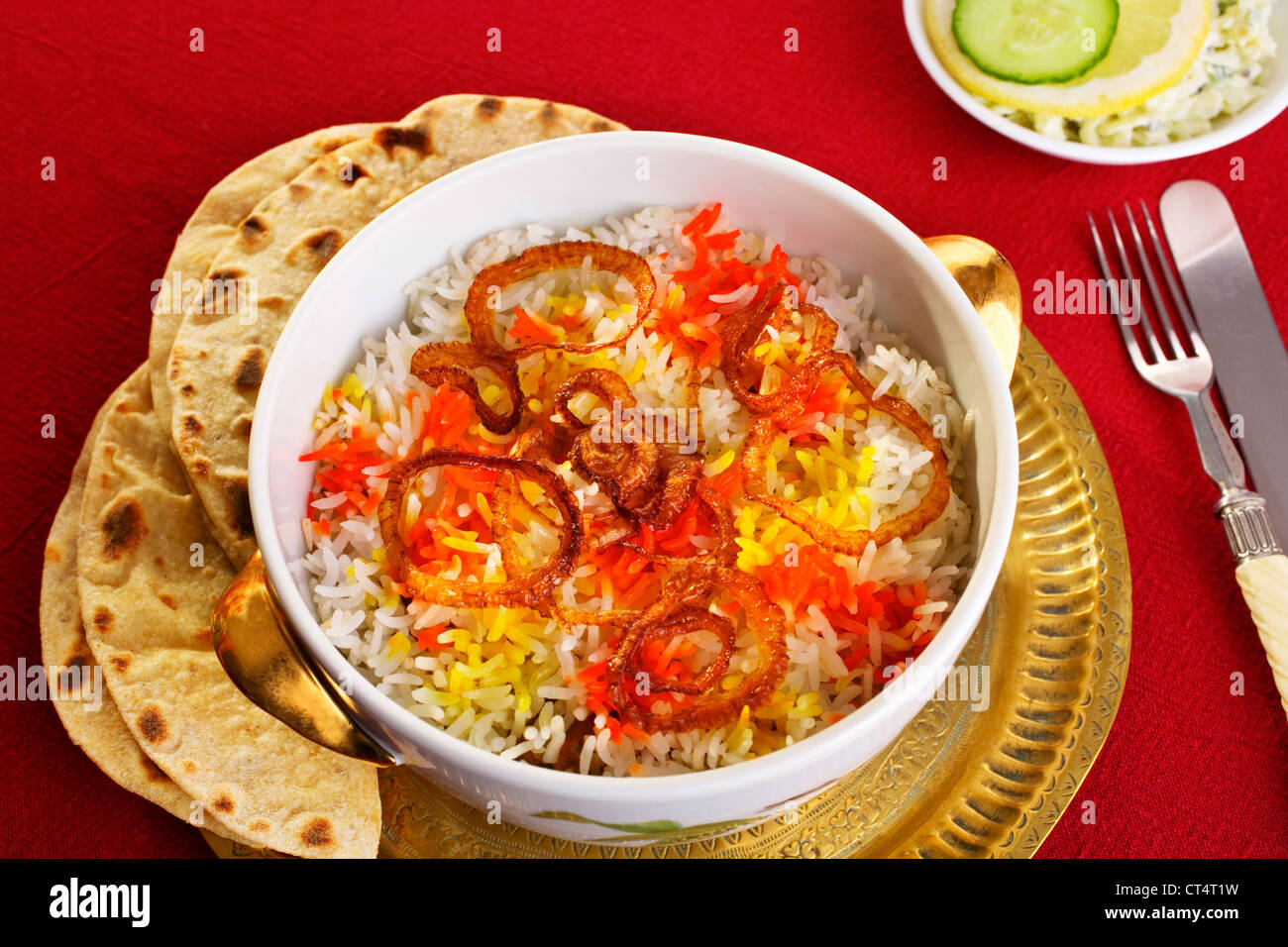 Luxurious lamb biryani, with red and yellow coloured rice and crisply fried onions, chapatis and chutney. Stock Photo