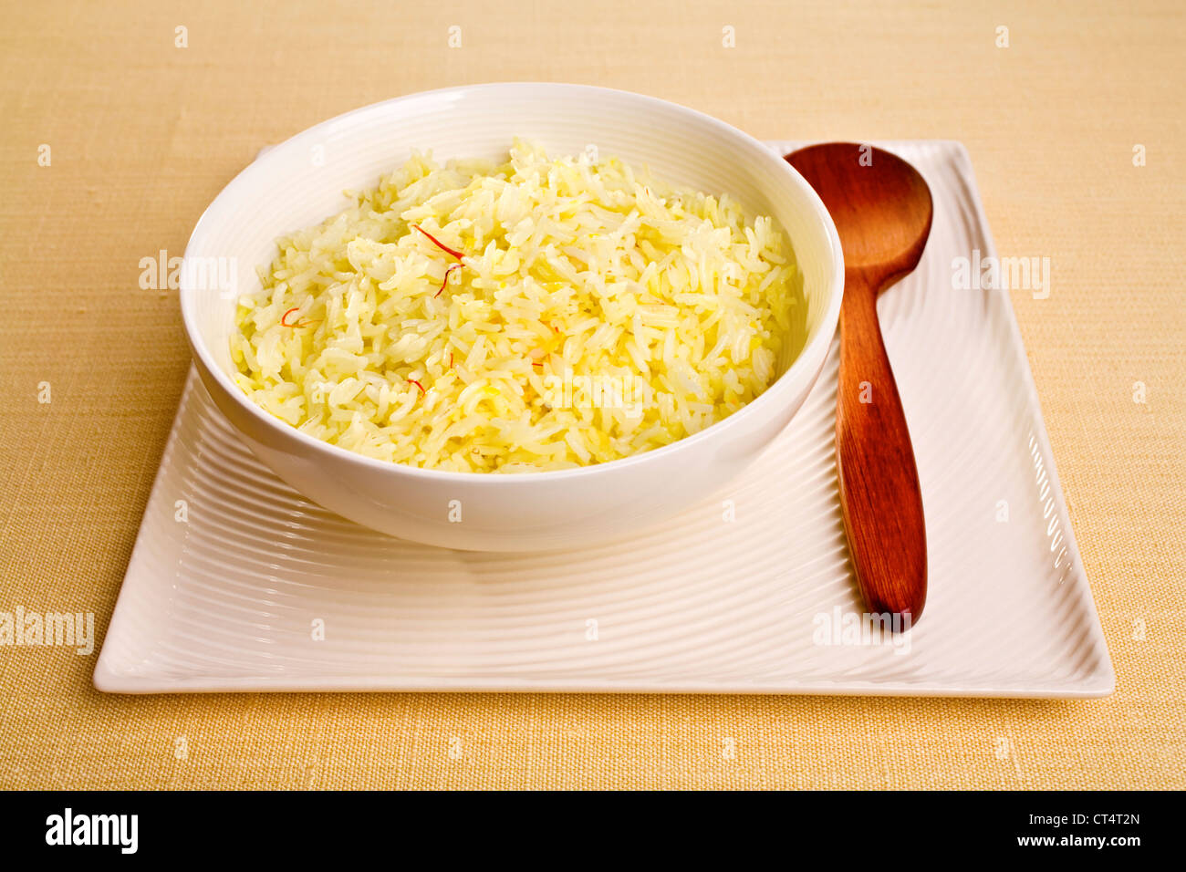 Basmati rice cooked with saffron, ghee and stock, in a round bowl set on a square plate. Stock Photo