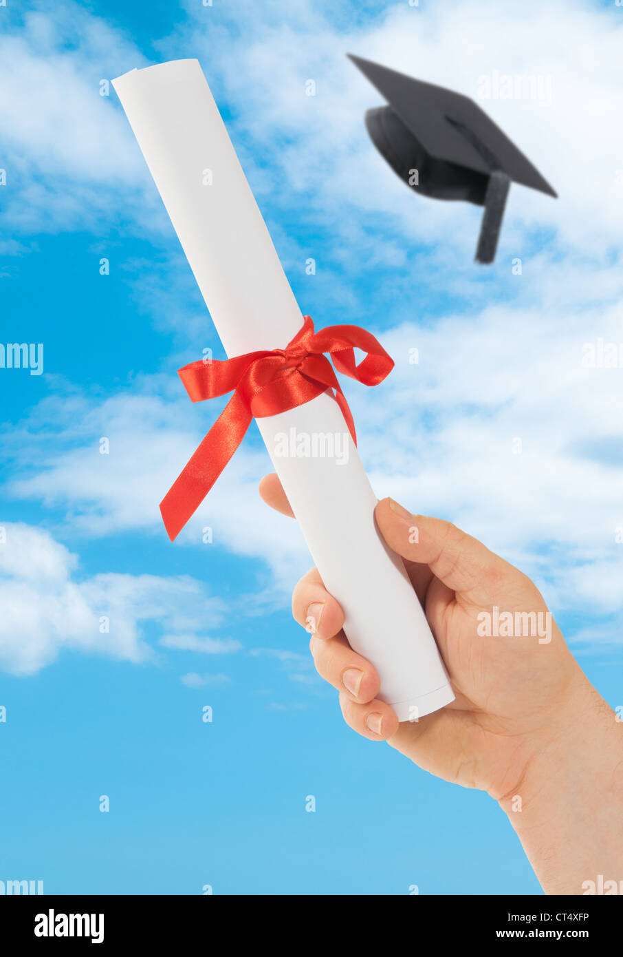 Graduation scroll held into the sky with mortar board Stock Photo