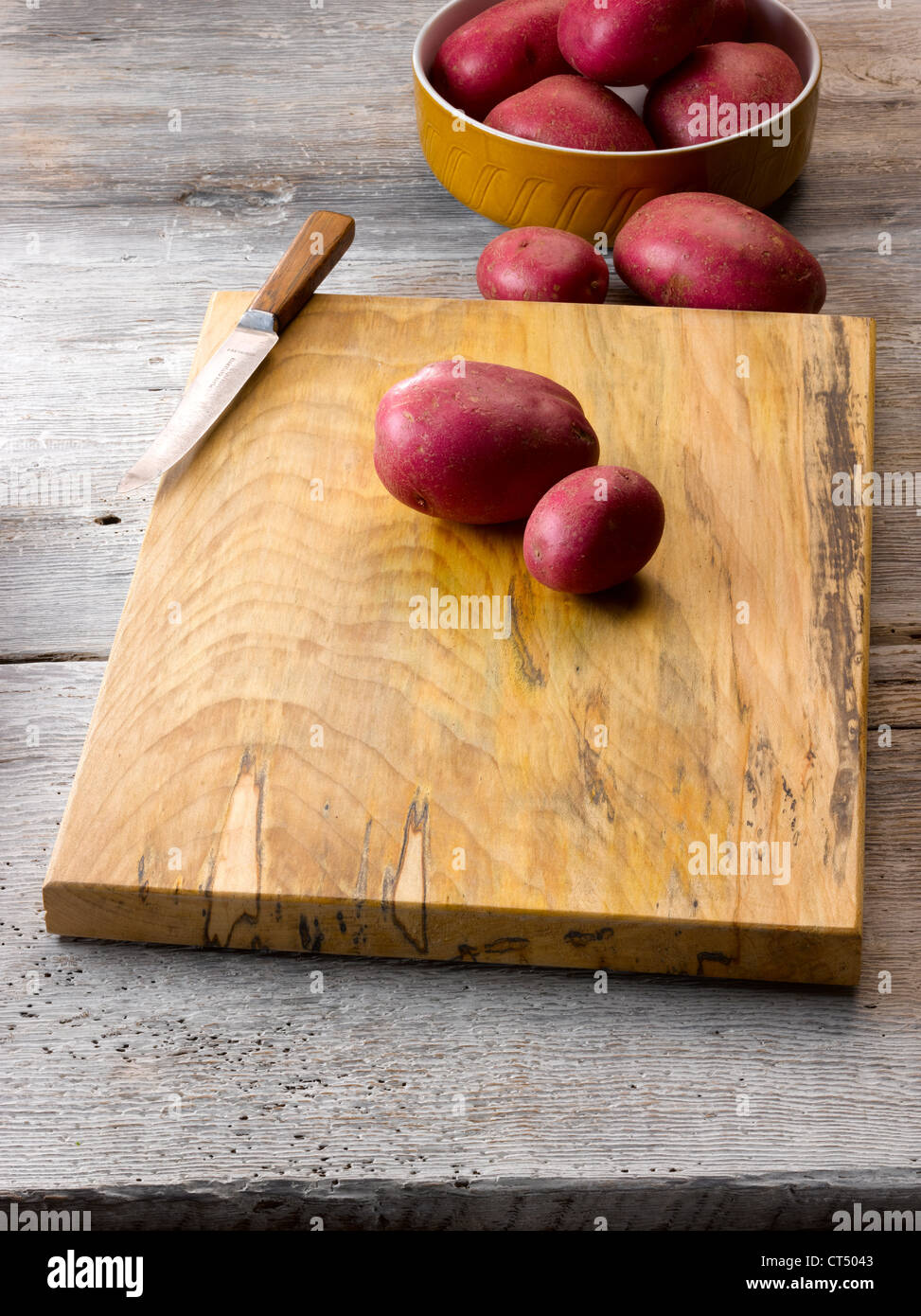 Rustic wood chopping board with raw potatoes Stock Photo