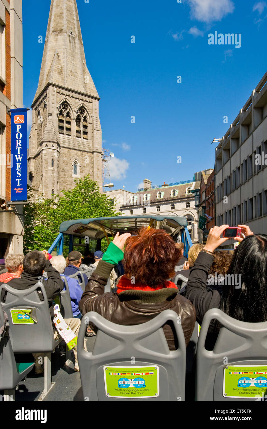 Tourists on a 'hop on hop off' city tour bus driving past St Andrews Church that now houses the Tourist Information Centre. Stock Photo