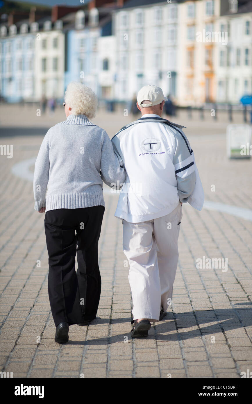 A senior elderly pensioner couple walking along aberystwyth promenade, Wales UK Stock Photo