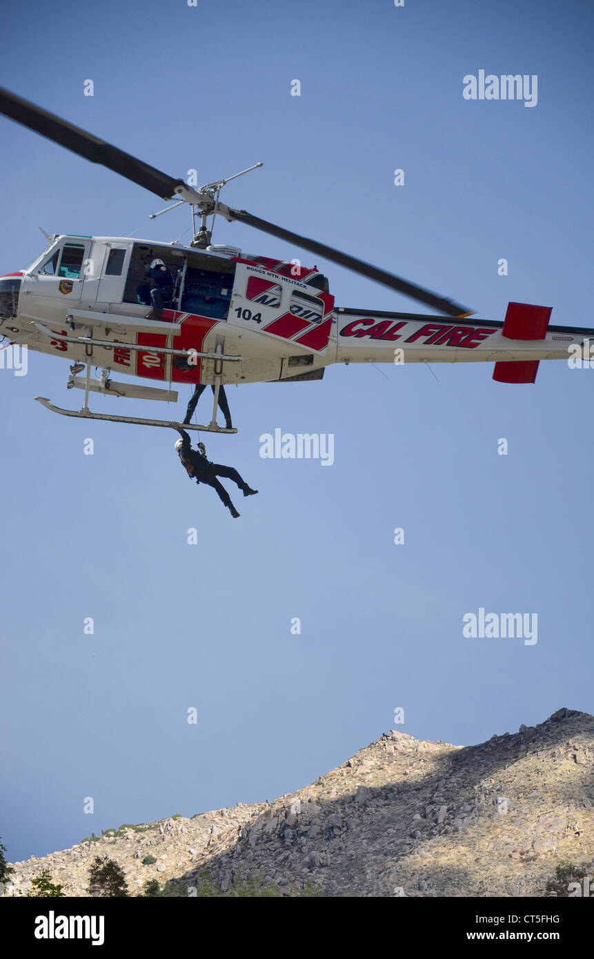 Photo of a hovering helicopter with a person grasping the landing skid. Taken during a Fire Department training exercise. Stock Photo