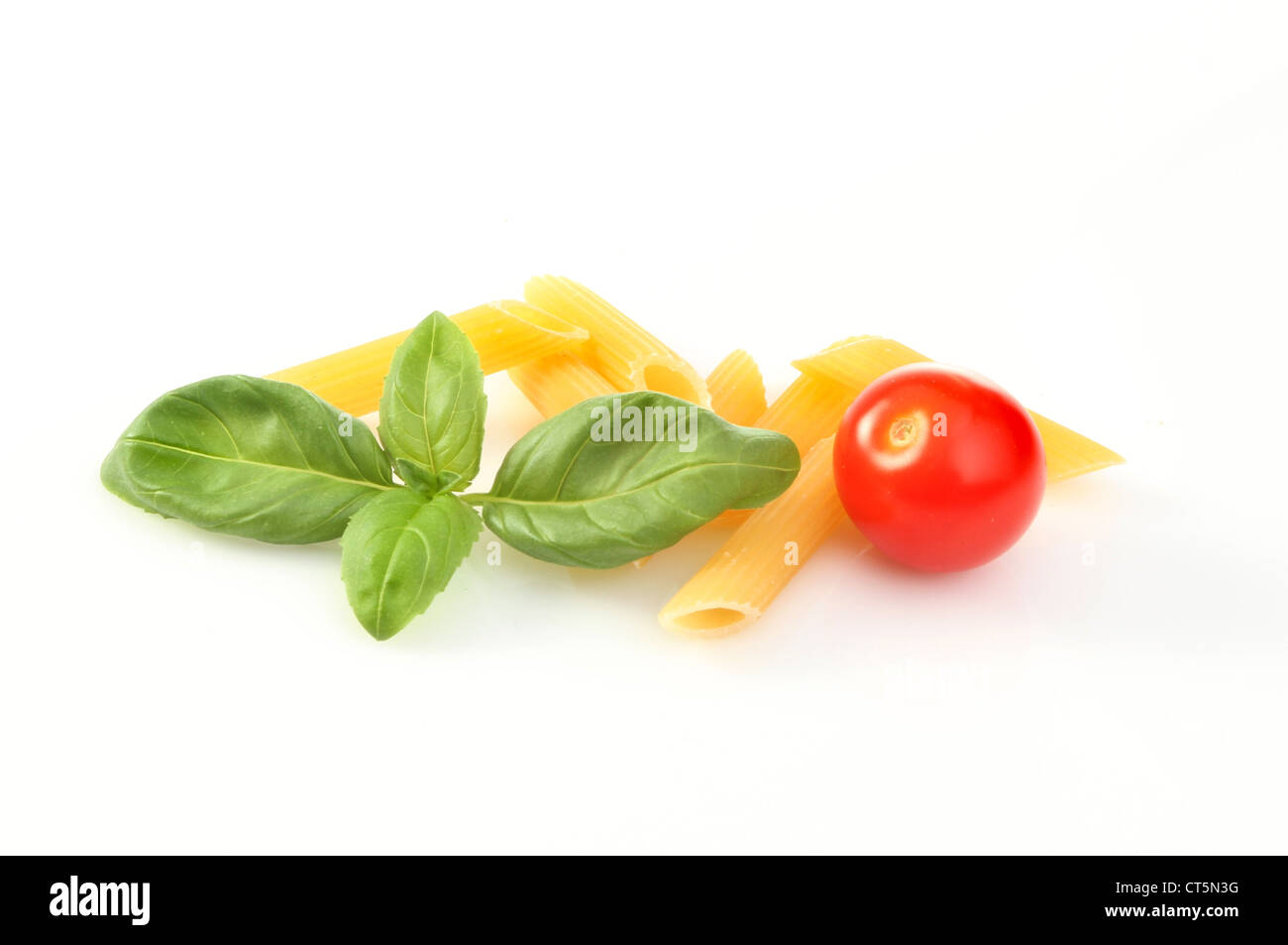 Basil penne pasta and a tomato on a white background Stock Photo