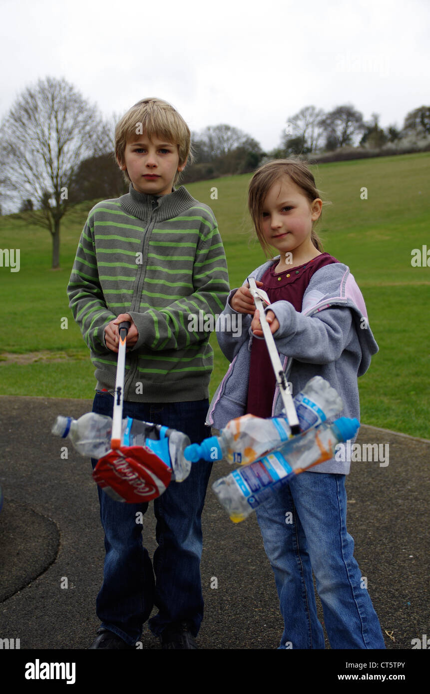 Children picking up litter in the playground in their local park Stock