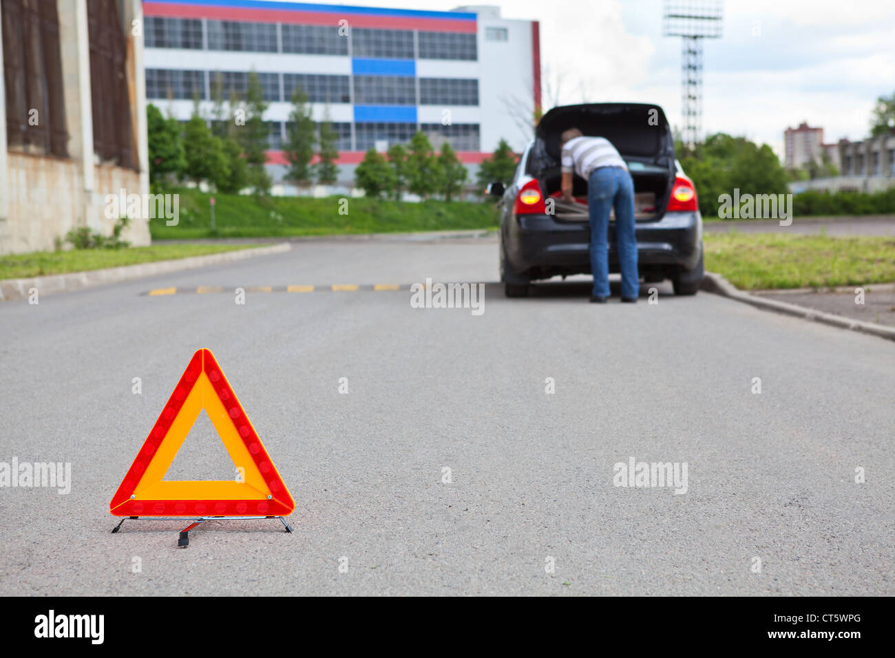 Triangle warning sign on road foreground and driver in car luggage rack ...