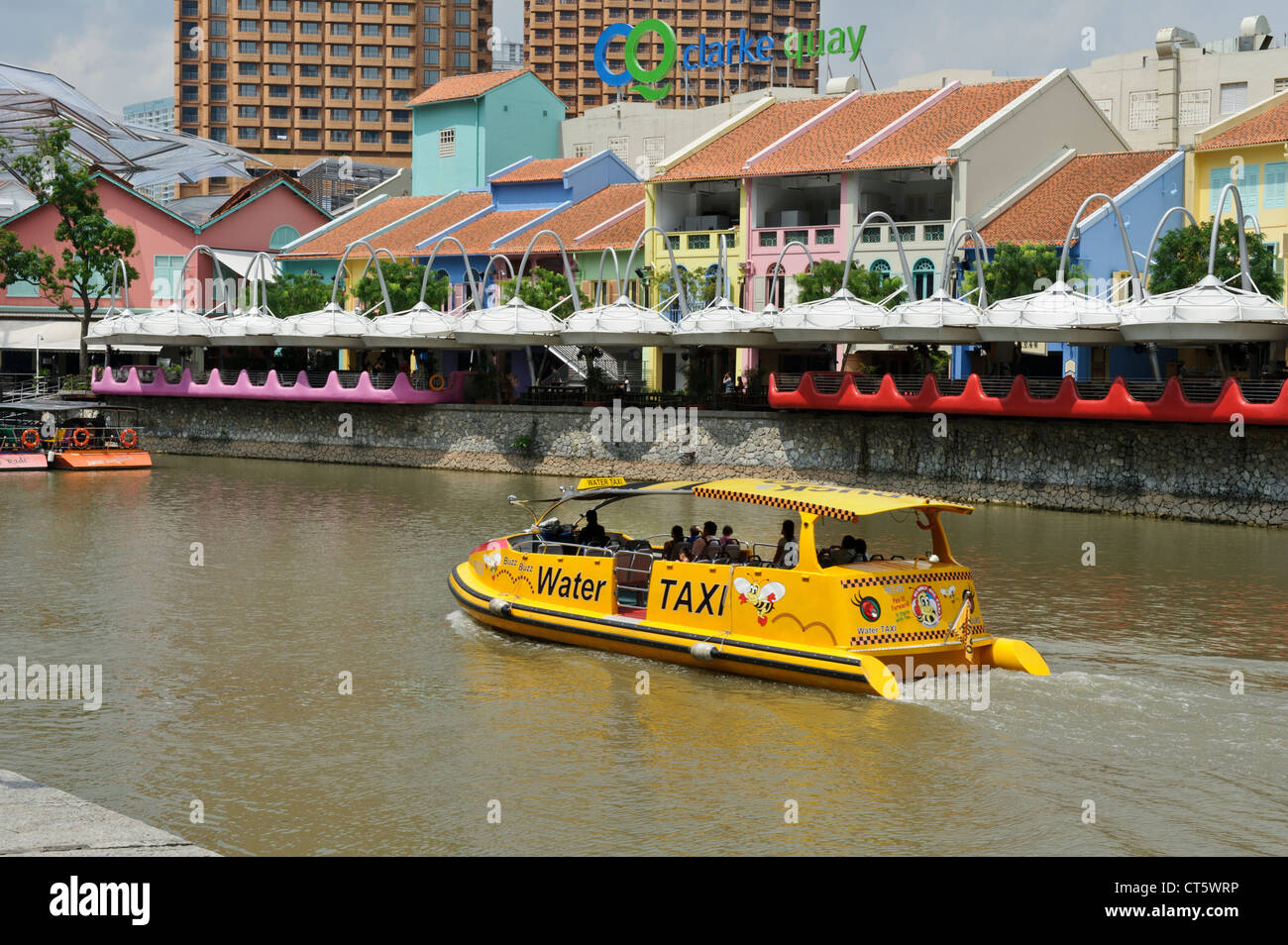 A yellow tourist boat traveling along the river near Clarke Quay, Singapore, Southeast Asia. Stock Photo