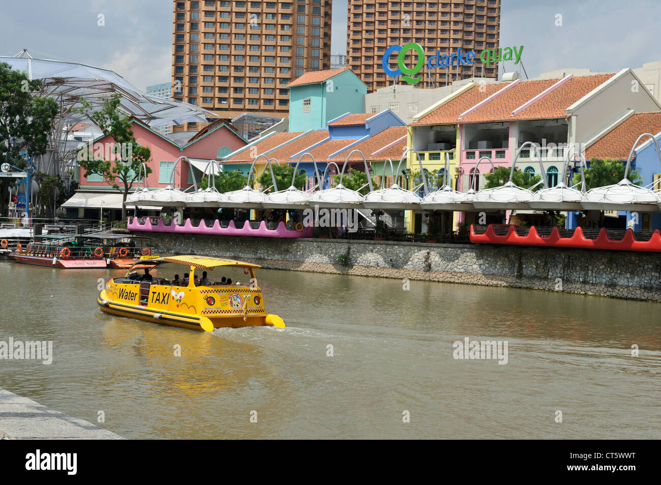 A yellow boat traveling along the river near Clarke Quay, Singapore, Southeast Asia. Stock Photo