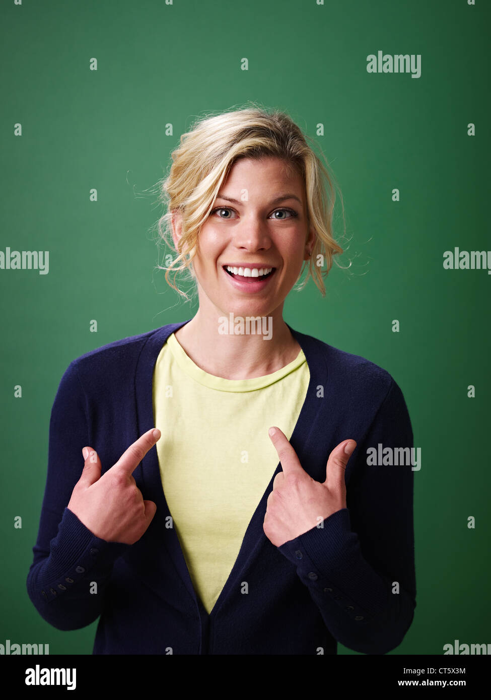 young woman pointing at herself against green background and looking at camera Stock Photo