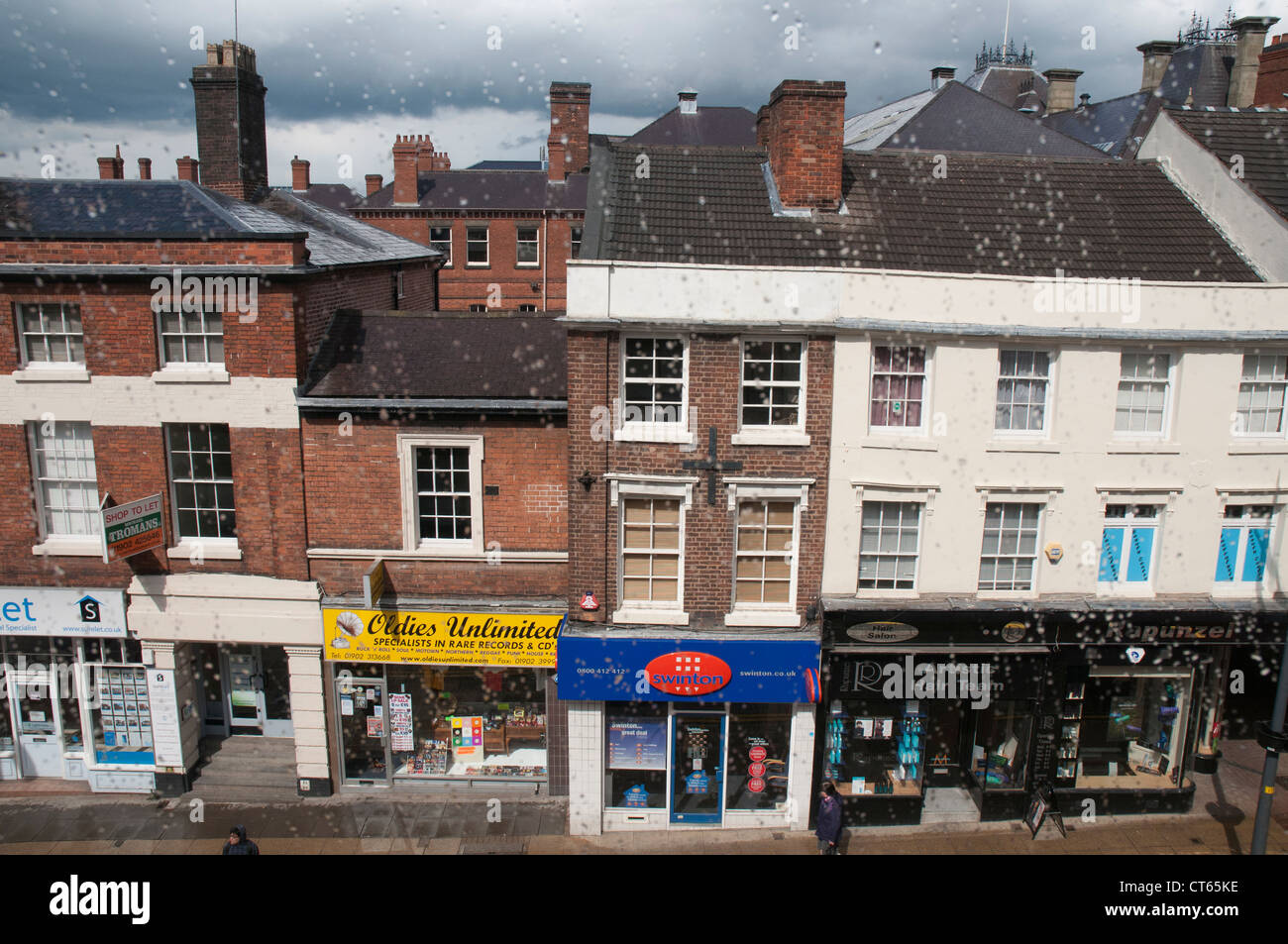 Shopfronts seen through a rain-streaked upstairs window in Wolverhampton, West Midlands Stock Photo